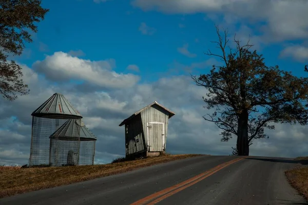 An isolated tree near an empty road and wooden buildings under the beautiful cloudy sky — Stock Photo, Image