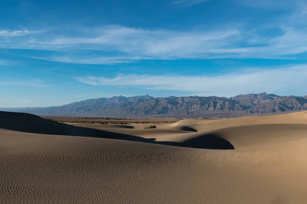 Piękne ujęcie pustyni ze śladami na piasku i skalistymi wzgórzami pod spokojnym niebem — Zdjęcie stockowe