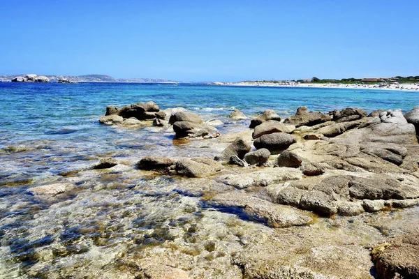 Beautiful scenery of a seashore with rocks of different sizes under the clear blue sky — Stock Photo, Image