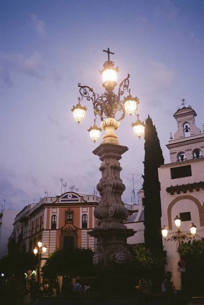 Imagen vertical de una luz de calle iluminada frente a hermosos edificios de hormigón bajo el cielo nublado — Foto de Stock