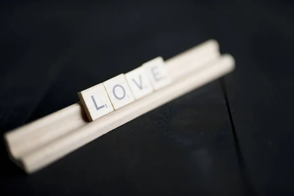 Primo piano colpo di ortografia blocco di legno amore su una superficie di legno nero — Foto Stock