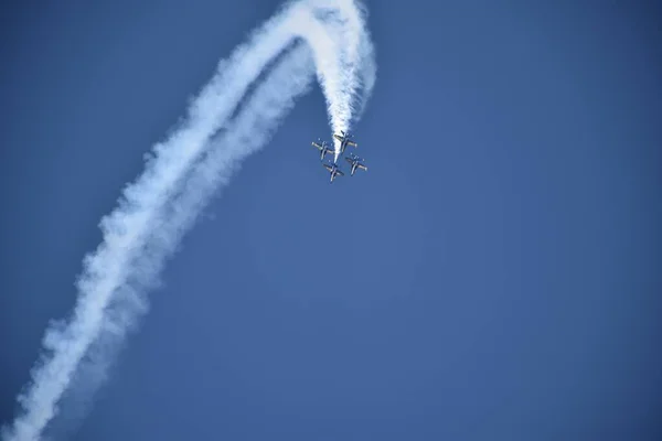 Tiefflug-Aufnahme von vier abfliegenden Flugzeugen mit Manövern, die eine riesige weiße Spur am Himmel hinterlassen — Stockfoto