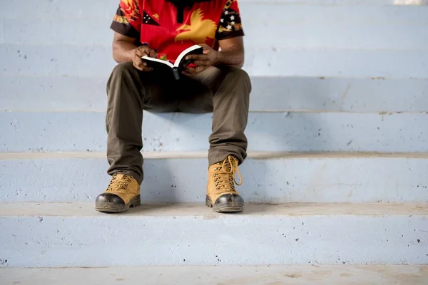 Человек, сидящий на лестнице, читая Библию — стоковое фото