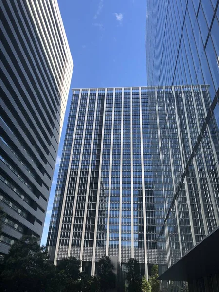 Låg vinkel skott av en glaskontorsbyggnad under den klarblå himlen i Tokyo, Japan — Stockfoto