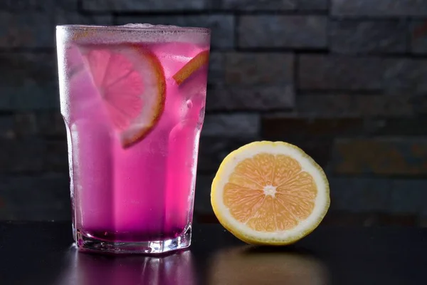 Ένα ποτήρι ροζ ποτό με μερικά λάιμ με σκούρο φόντο — Φωτογραφία Αρχείου