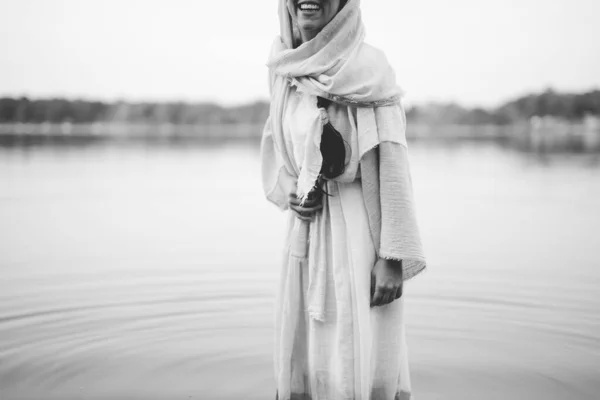 Female wearing a biblical robe and smiling with a blurred background in black and white