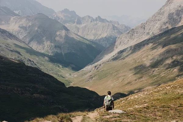 A behind shot of the hiker with mountains on the background