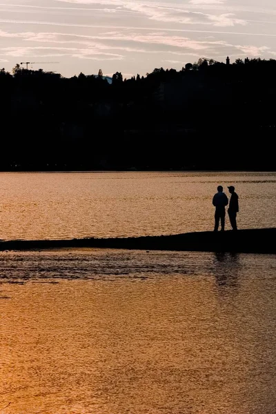 Plan Vertical Silhouette Deux Personnes Debout Bord Lac Près Colline — Photo