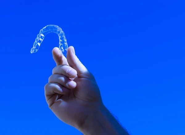 Крупный План Руки Прозрачным Ортодонтическим Прибором Синем Фоне — стоковое фото