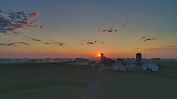 Ένα Μαγευτικό Ηλιοβασίλεμα Στην Ύπαιθρο Συννεφιασμένο Ουρανό Και Αγροτικά Σπίτια — Φωτογραφία Αρχείου