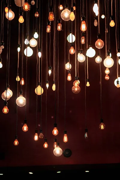 A vertical shot of colorful modern light bulbs hanging from the ceiling