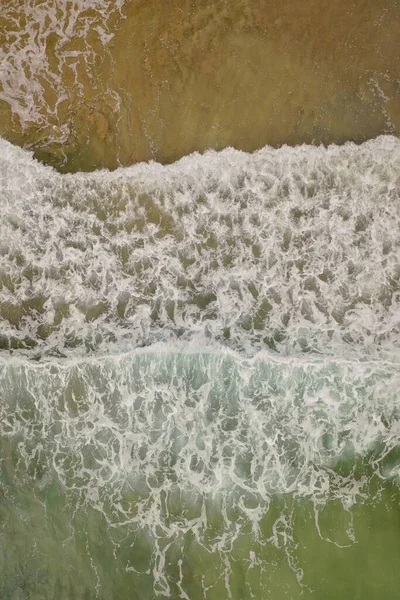 昼間の海岸での純粋な緑色の水の波のオーバーヘッドショット — ストック写真