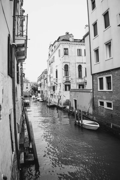 Vertikální Snímek Kanálu Stupních Šedi Loděmi Starobylými Budovami Benátkách Itálie — Stock fotografie