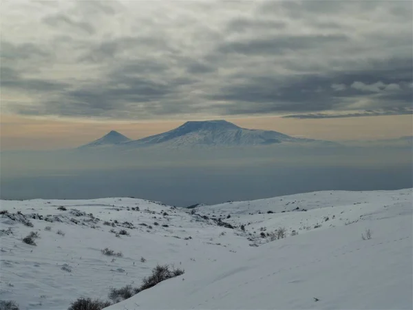 暗い雲の下に高い山を望む雪景色 — ストック写真