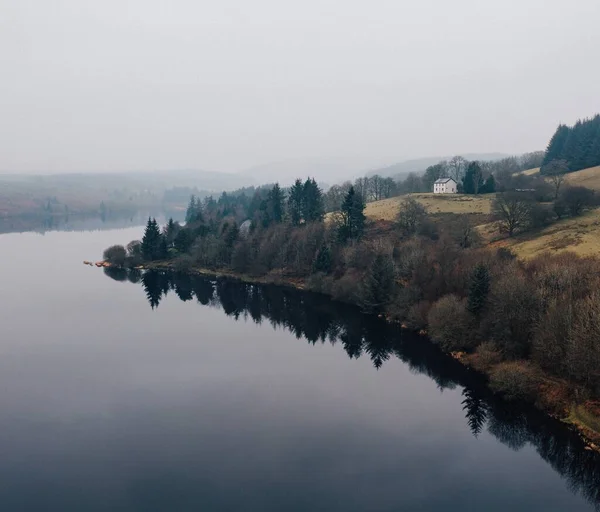 Uma Casa Uma Colina Coberta Árvores Por Belo Lago Capturado — Fotografia de Stock