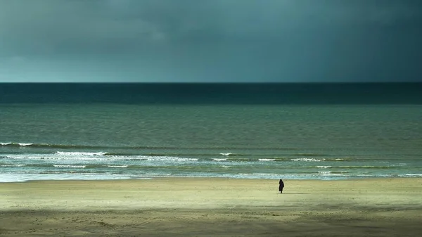 구름낀 하늘을 배경으로 모래가 해변에서 사람의 — 스톡 사진