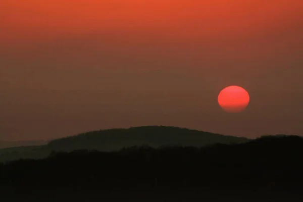 山々のシルエットの上に魅惑的な赤い太陽の美しい写真 — ストック写真