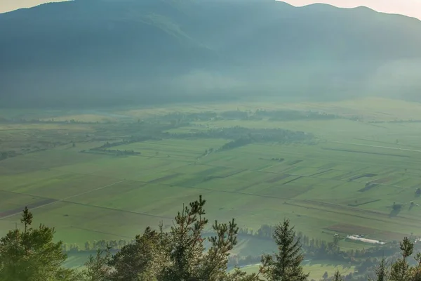 スロベニアのスリヴニツァ山の麓にあるかすんだ緑の農地の景色 — ストック写真