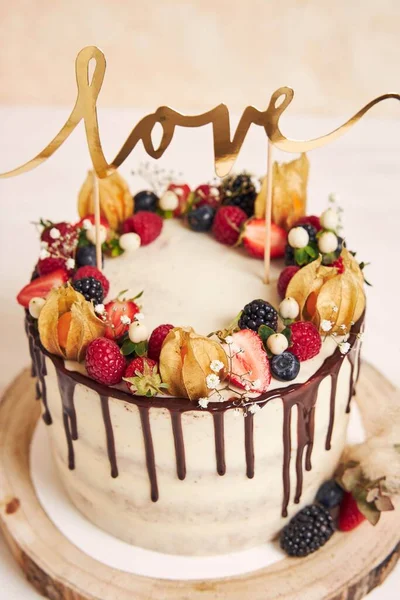 フルーツチョコレートドリップとラブトッパー付きの美しいウェディングケーキの垂直ショット — ストック写真