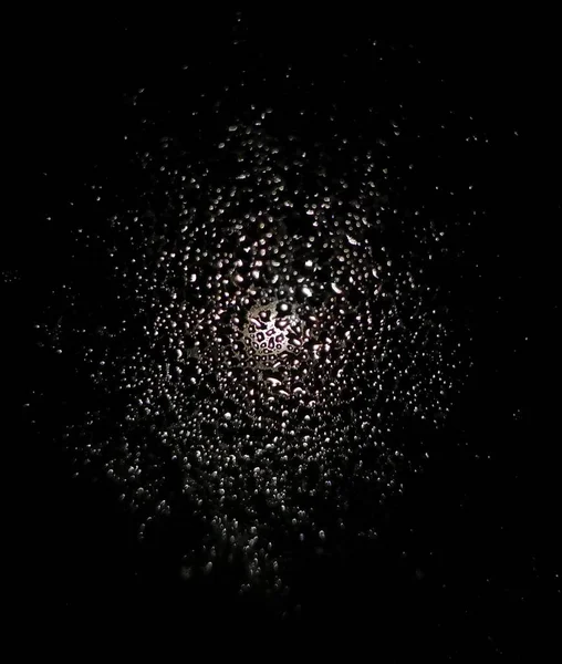黒い表面の水滴の上に輝く光の塊 — ストック写真