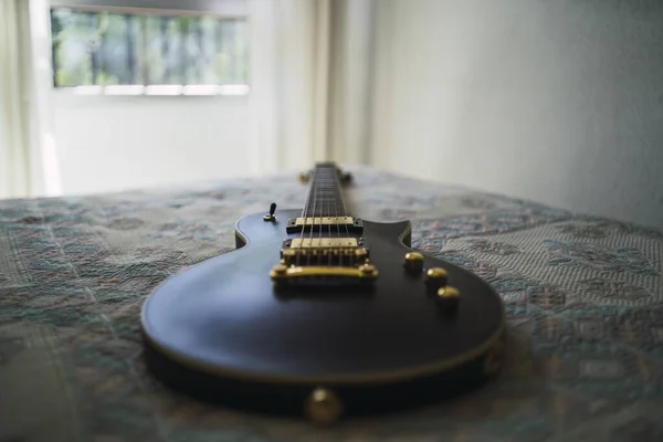 Siyah Bir Elektro Gitarın Yakın Plan Fotoğrafı Yatağın Üzerinde Desenli — Stok fotoğraf