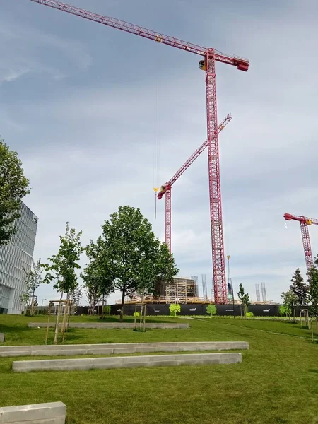 Vertical Shot Red Construction Cranes Surrounded Greenery Cloudy Sky Daytime — Stock Photo, Image