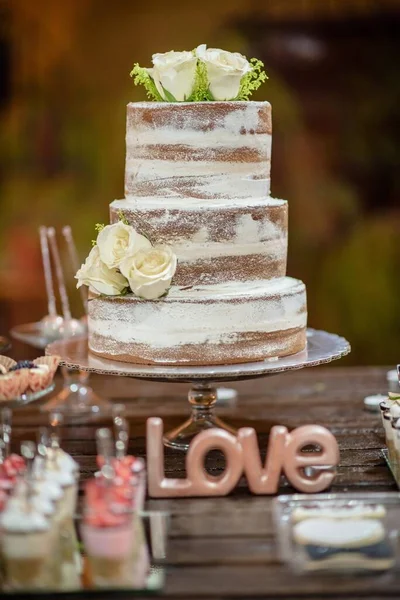 新鮮なバラで飾られた3層の裸の結婚式のケーキと 愛を読む言葉の装飾 — ストック写真