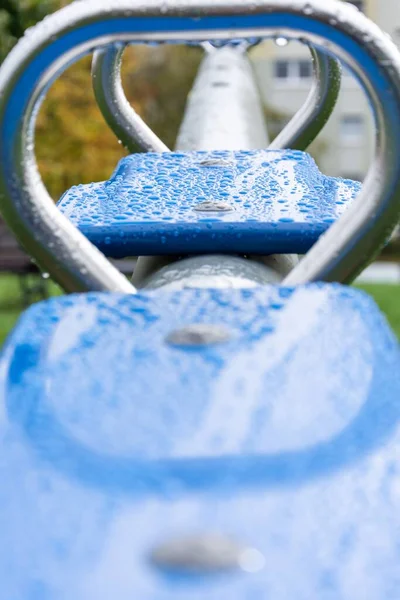 Eine Vertikale Selektive Fokusaufnahme Von Blauen Outdoor Turngeräten Mit Wassertropfen — Stockfoto