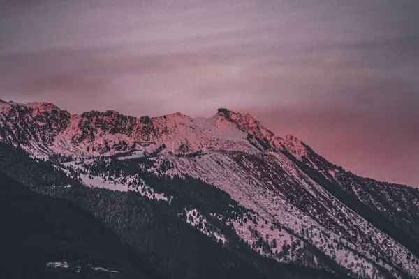 カラフルな夕暮れ時に撮影された雪で覆われた山のピークの低角度ショット — ストック写真