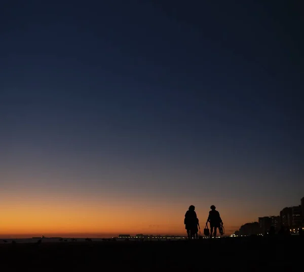Ένα Σκηνικό Σιλουέτας Ανθρώπους Ρυμούλκησης Που Περπατούν Μαζί Ηλιοβασίλεμα — Φωτογραφία Αρχείου