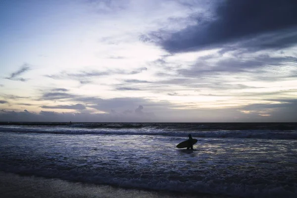 Mężczyzna Deską Surfingową Plaży Podczas Wschodu Słońca — Zdjęcie stockowe