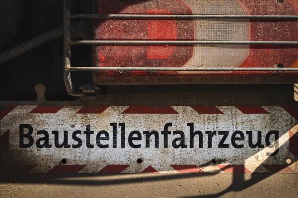 ドイツ語で 建設車両 と書かれたトラックの後ろの光の下での標識 — ストック写真