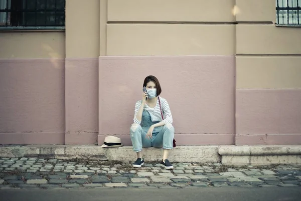 Uma Jovem Mulher Com Uma Máscara Facial Sentada Calçada Conversando — Fotografia de Stock