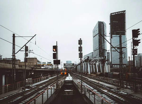 Şehirdeki Yüksek Binalarla Demiryolunda Seyahat Eden Turuncu Bir Tren — Stok fotoğraf