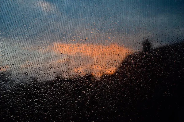 用雨滴覆盖的杯子拍的特写镜头 背景中可以看到日落 — 图库照片