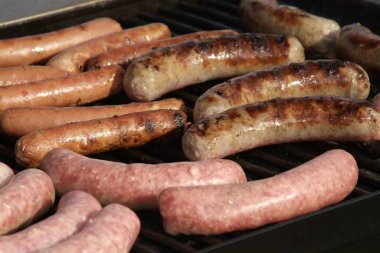 A closeup shot of delicious sausages being grilled on the bbq grill clipart