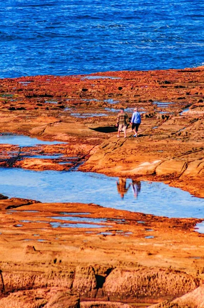 Vertical Shot Two People Walking Rocky Shore Sea — Stock Photo, Image