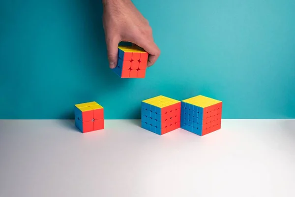 Gros Plan Une Personne Mettant Différentes Tailles Rubik Cube Sur — Photo