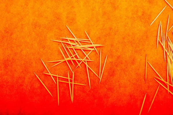 The toothpicks on an orange surface -background