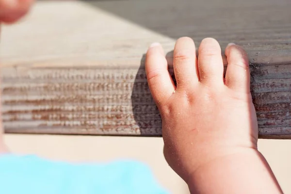日光の下で木の表面にかわいい赤ちゃんの手のクローズアップショット — ストック写真