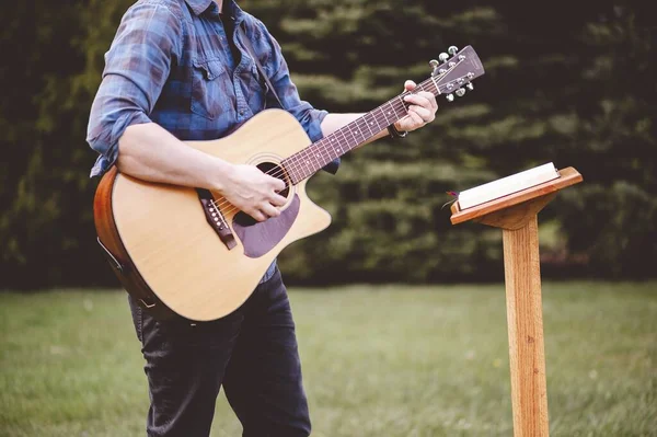一个拿着吉他站在绿色草坪上的男人 — 图库照片
