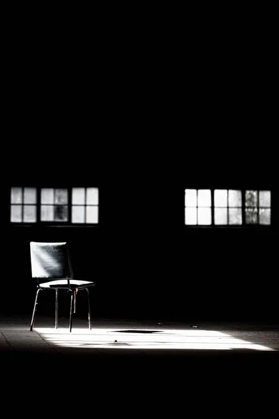 Вертикальний Знімок Порожнього Стільця Темній Кімнаті Невеликим Світлом Виходить Вікна — стокове фото