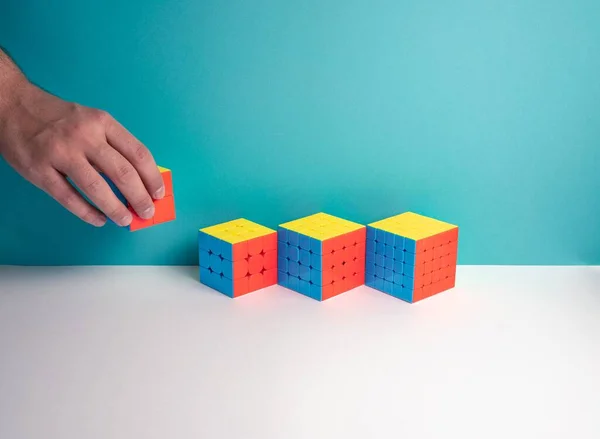 Gros Plan Une Personne Mettant Différentes Tailles Rubik Cube Sur — Photo