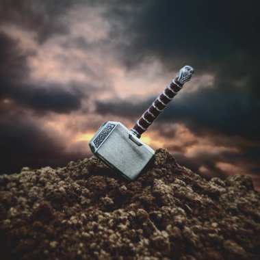 A close up shot of the hammer of Thor stuck in the ground clipart