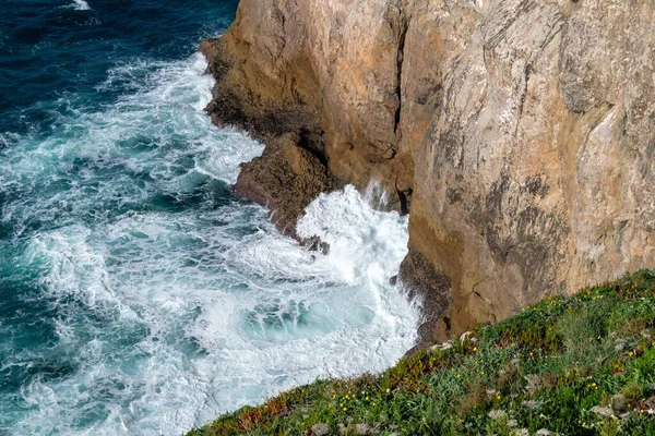 太陽の光の下で緑と岩に囲まれた波状の海の高角度ショット 壁紙に最適 — ストック写真