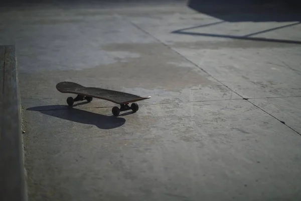 昼間の公園のコンクリートの床に黒いスケートボードの浅いフォーカスショット — ストック写真