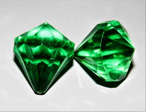 Eine Nahaufnahme Von Zwei Grünen Kristallen Auf Einer Grauen Oberfläche — Stockfoto
