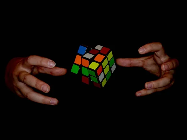 Siyah Arka Planda Elleri Ile Çevrili Rubik Küpünün Manzara Görüntüsü — Stok fotoğraf