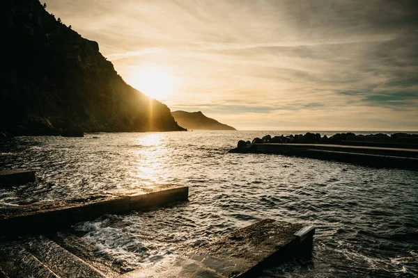 岩だらけの丘に囲まれた海に映る夕日の美しい景色 — ストック写真