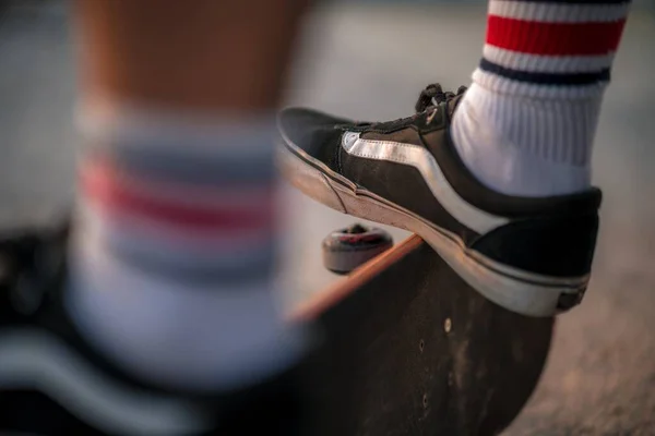 身穿白袜和黑色运动鞋的男足穿上黑色滑板 — 图库照片